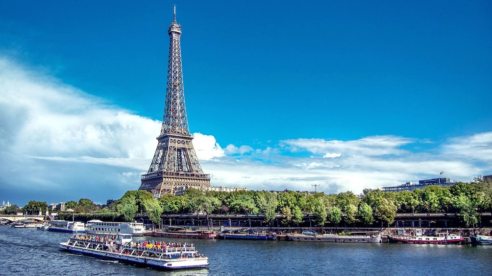 Seine river cruise boat sails past Eiffel Tower in Paris