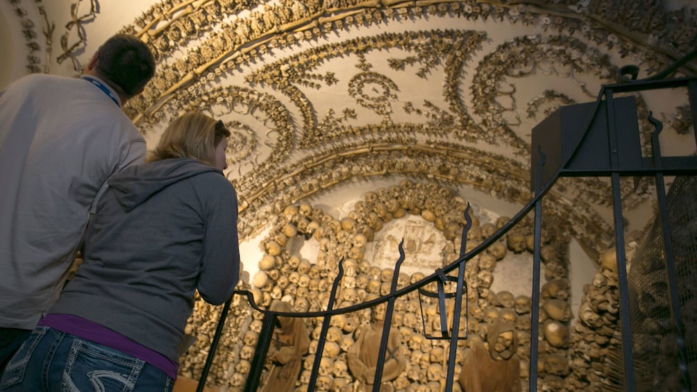 Couple looking at bones and skulls adorning the walls of the catacombs in Rome