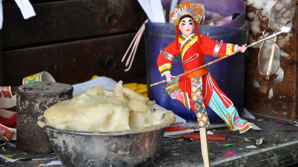 A bowl of white mush and a doll with a spear