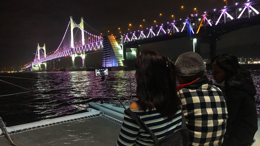 Three people on a yacht at night in Busan, South Korea at night