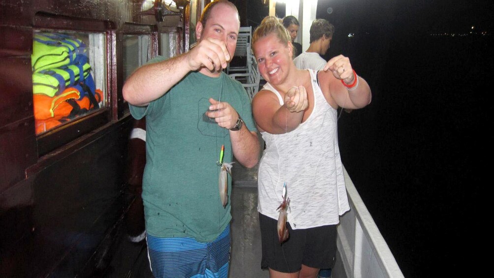 Couple holds up squids caught in Hanoi