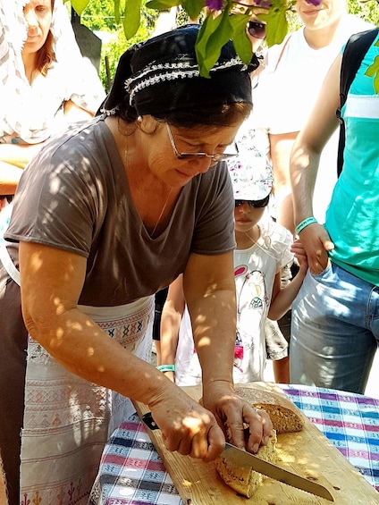 Woman slicing bread on a table outdoors in Cyprus