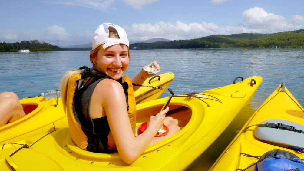 Woman eats a oyster in a Kayak