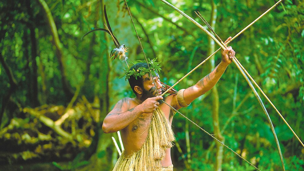 Men dressed in indigenous clothing to Vanuatu Island and holding a bow and arrow