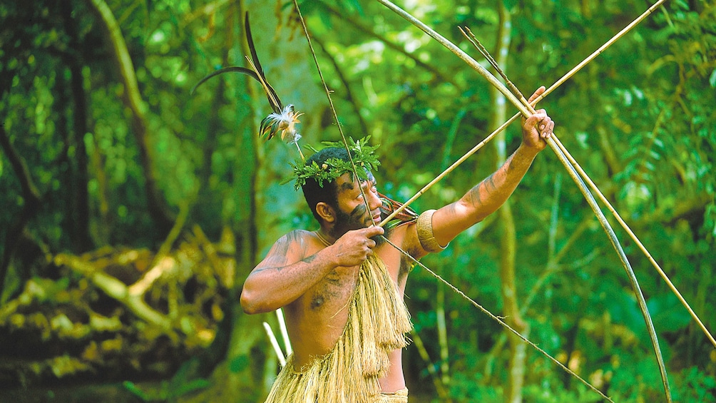 Men dressed in indigenous clothing to Vanuatu Island and holding a bow and arrow