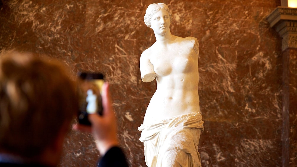 Tourist taking picture of statue in the Louvre