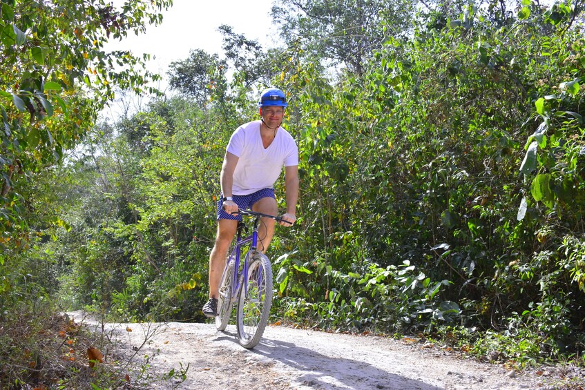 Man bikes on sunny path in Playa del Carmen, Mexico