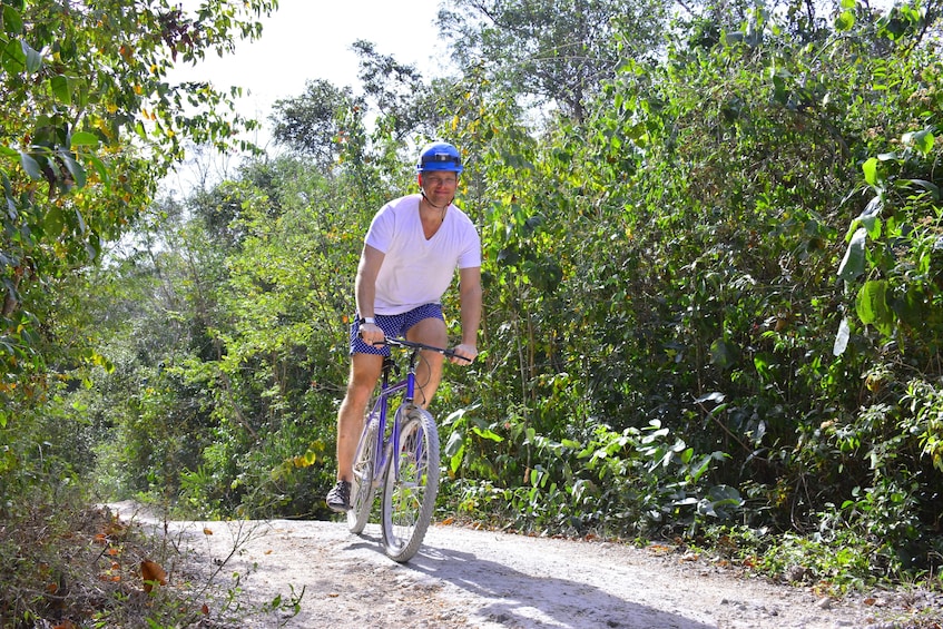 Man bikes on sunny path in Playa del Carmen, Mexico