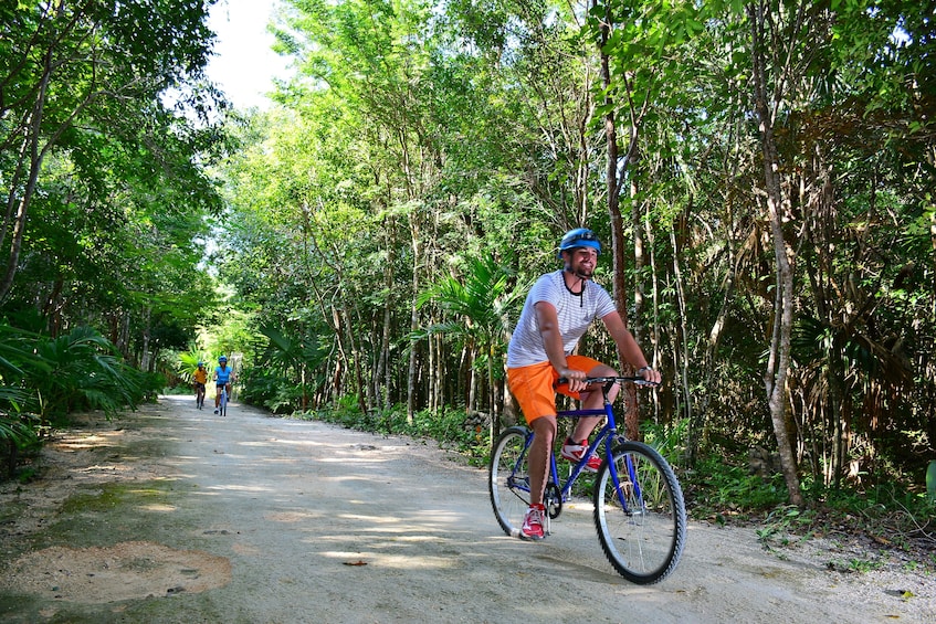 Man bikes along shaded path in Playa del Carmen, Mexico