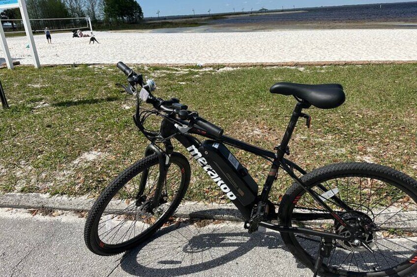 Electric Mountain Bike parked in front of the sandy beach at St. Cloud Lakefront Park.