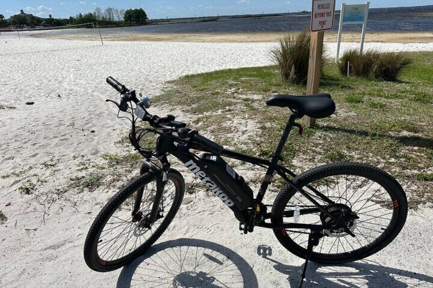 Electric Mountain Bike parked next to the sandy beach in St. Cloud where swimming is permitted! Just keep an eye out for gators...