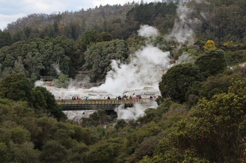 People looking out over waterfall on bridge in Hobbiton in New Zealand