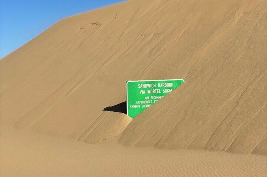 Sandwich harbour road sign being devoured by the ever moving dunes