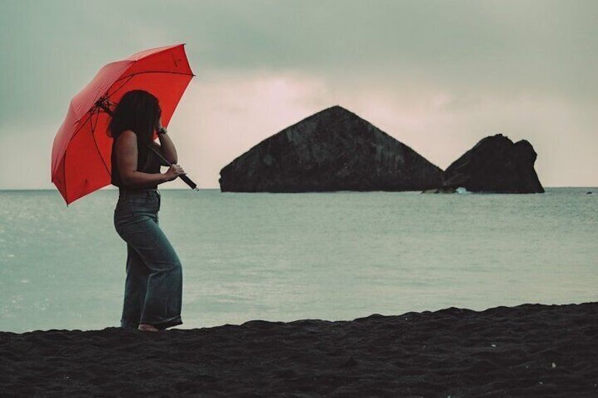 A stunning woman from the U.S.A. adding a pop of color with her red umbrella, set against the beautiful beach and islets backdrop