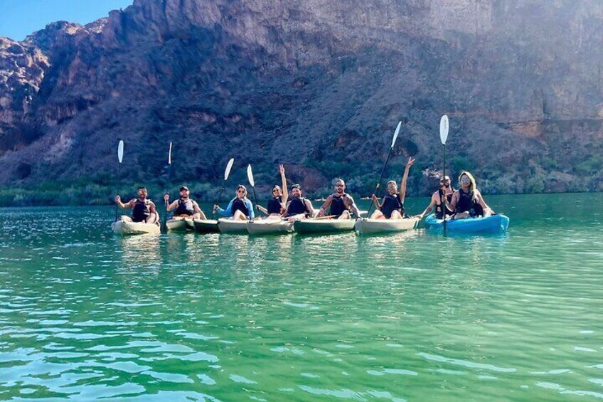 A group of kayakers hold their paddles in the air for some fun. 