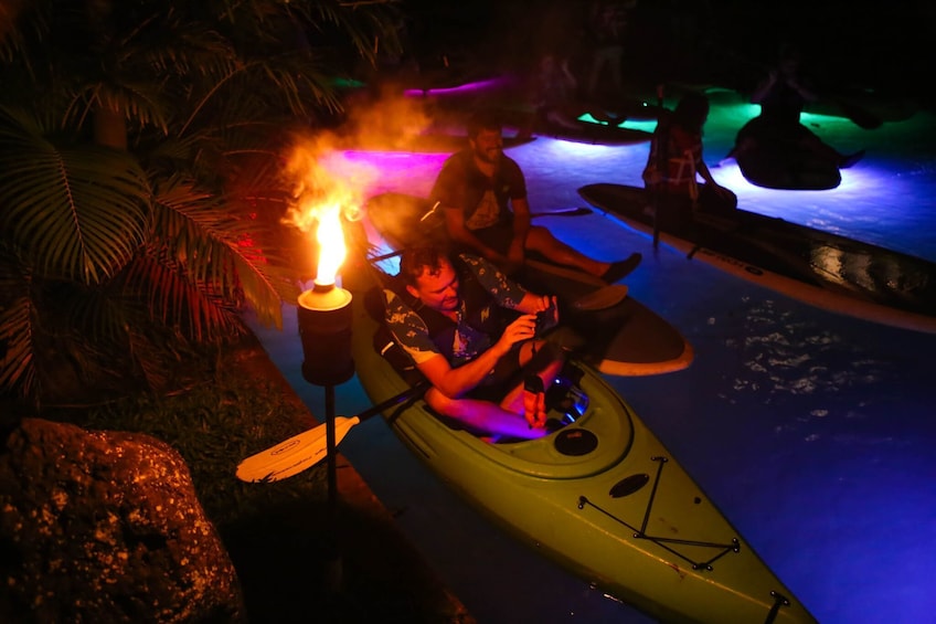 Kayaker takes photo at night on illuminated pool