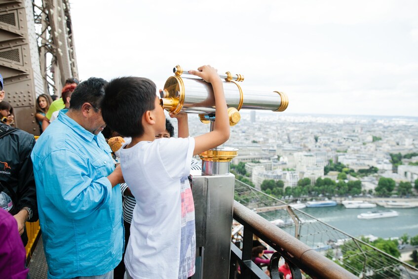 Kid looking through a viewfinder from the Eiffel Tower in Paris