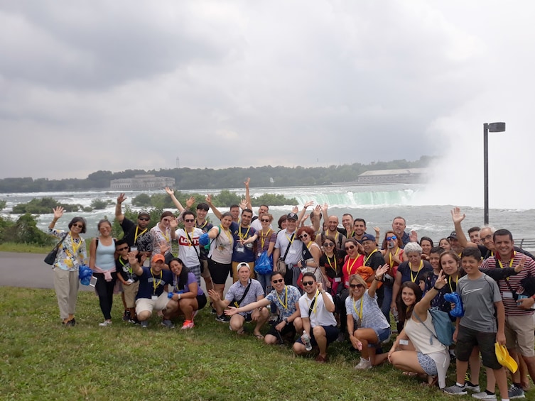 Tour group posed and waving in front of Niagara Falls