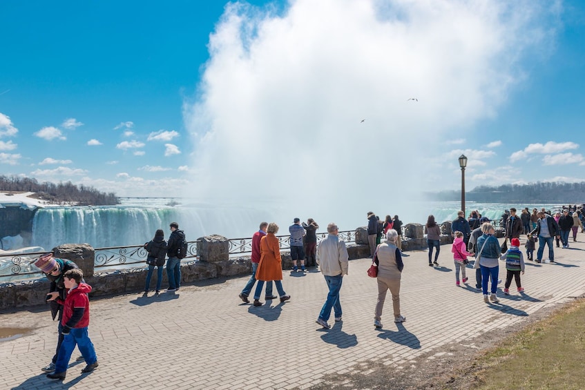 People strolling in front of a misty Niagara Falls