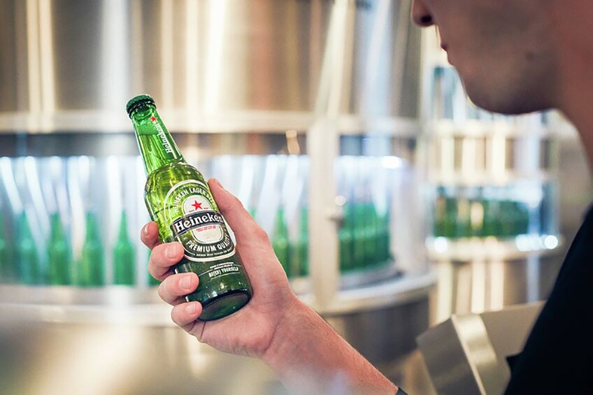Guest holding a Heineken® bottle at the Heineken® Experience tour in Amsterdam