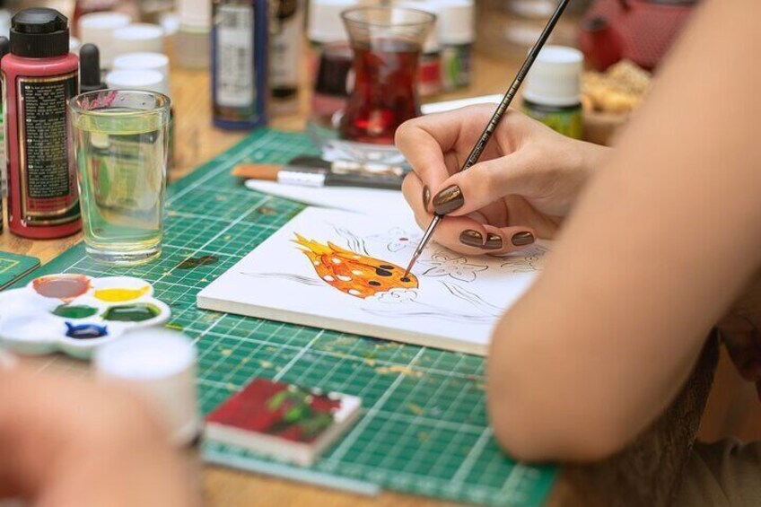 Participant carefully painting a Turkish tile design during an Istanbul art workshop