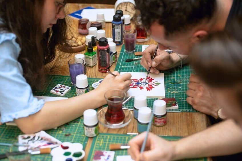 Group of participants collaborating on traditional Turkish tile painting at a workshop in Istanbul.