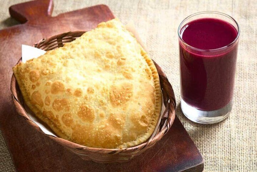 thick drink based on Bolivian purple corn accompanied by a pastry filled with cheese and covered with powdered sugar