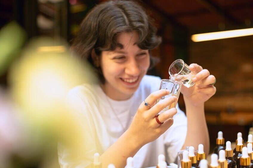 Smiling participant enjoying the creative process during a perfume making workshop in Istanbul