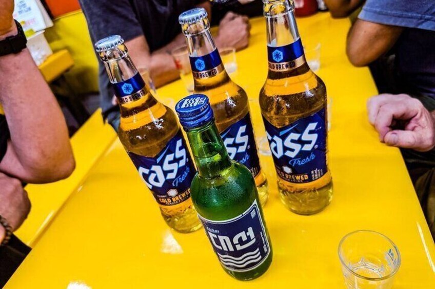 A lively market table featuring Korea’s iconic Cass beer and a bottle of soju, the quintessential duo for a night of local food and camaraderie.