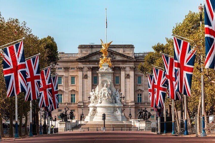 Buckingham Palace, adorned with Union Jack flags, stands majestically behind the Victoria Memorial, a symbol of British royalty.