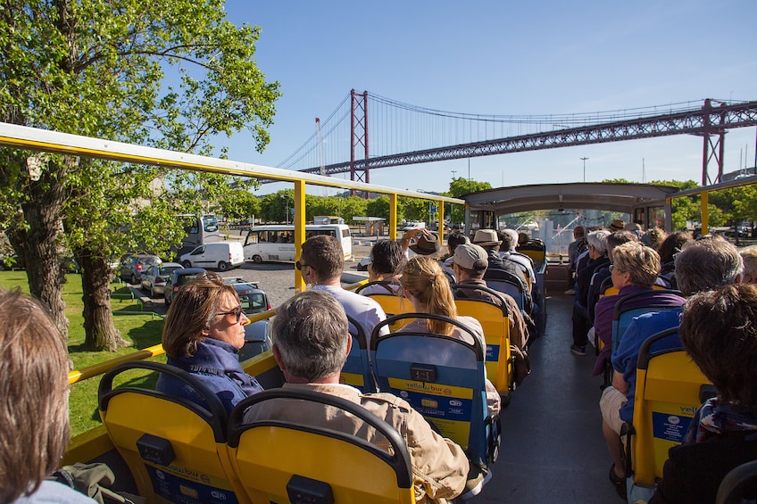 Tour bus headed towards a bridge in Lisbon on a sunny day