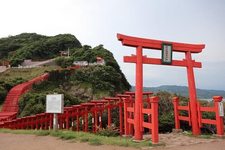 The Motonosumi Shrine's torii tunnel, with 123 red torii gates stretching along the hillside to the edge of a cliff, creates a breathtaking landscape with the blue sky,