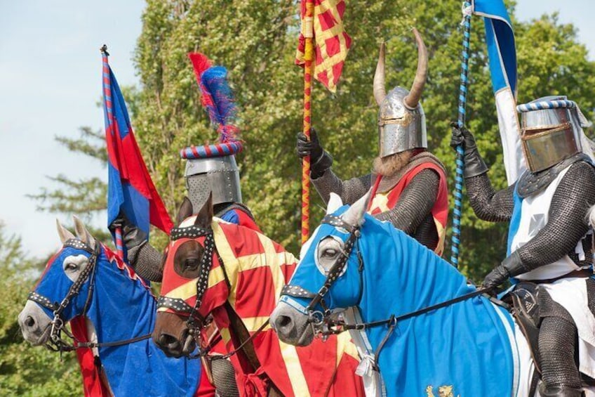 Knights in armor prepare for a jousting event at Hever Castle, showcasing a vibrant medieval re-enactment, complete with colorful banners and armored horses.