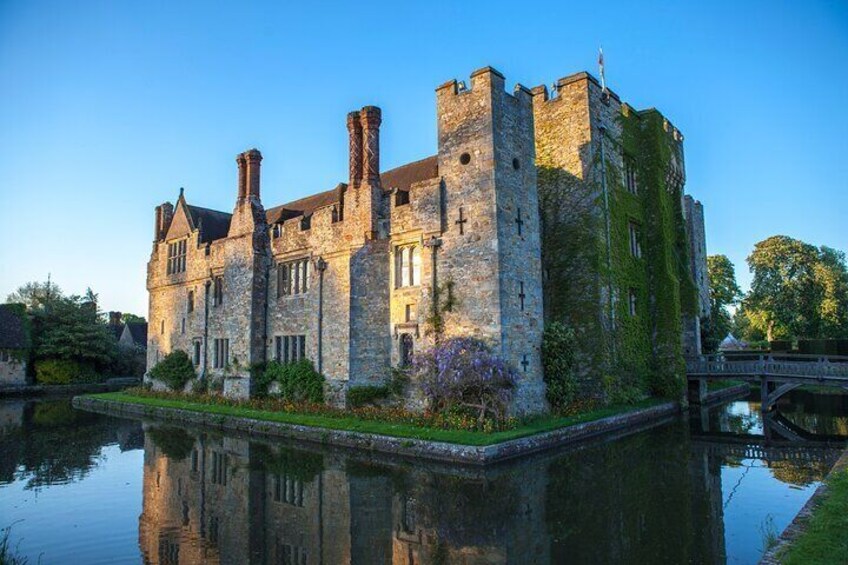 The majestic Hever Castle, once the childhood home of Anne Boleyn, stands surrounded by a picturesque moat, basking in the soft evening light.