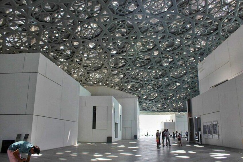 Under the Louvre Abu Dhabi's dome, visitors are immersed in an artistic sanctuary that harmonizes light, art, and architecture.
