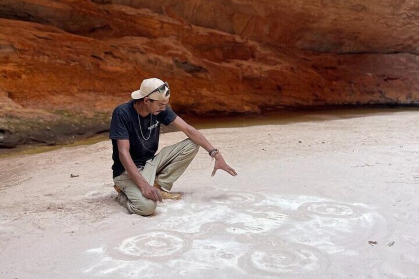 Sand drawing with Kingfisher tours custodian for country Aboriginal guide Kolya in Cathedral Gorge in the Bungle Bungle.