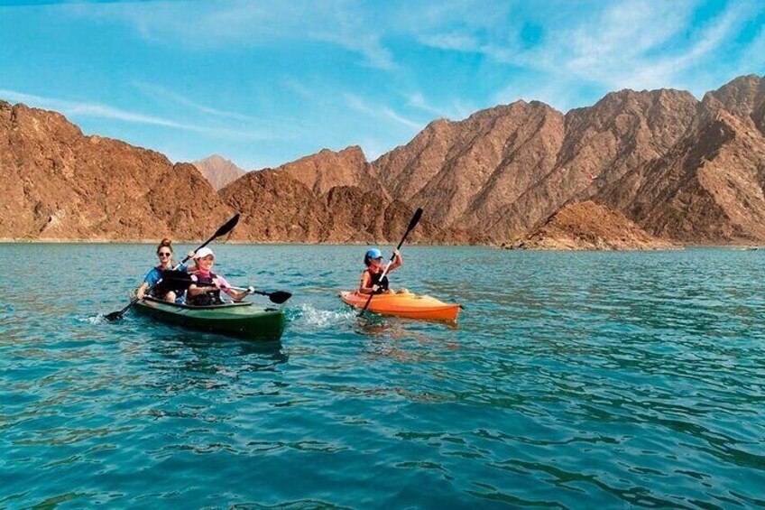 Visitors enjoy a relaxing kayaking experience at Hatta Dam, surrounded by stunning mountain views and tranquil waters.