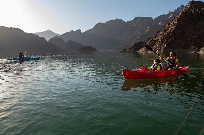 Kayakers enjoying the peaceful waters of Hatta Dam, surrounded by the breathtaking natural beauty of the mountains.