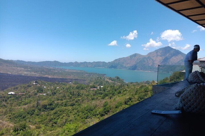 Enjoy traditional Balinese food at a cafe near Mount Batur with a view of the blue lake and Mount Batur.