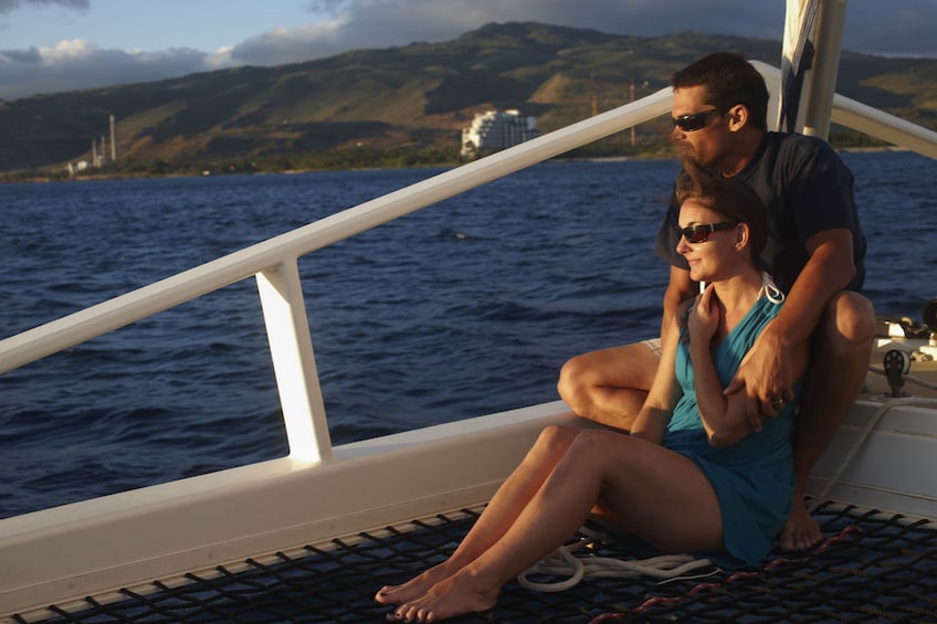 Couple taking in views of the sunset in Waikiki while on a boat 