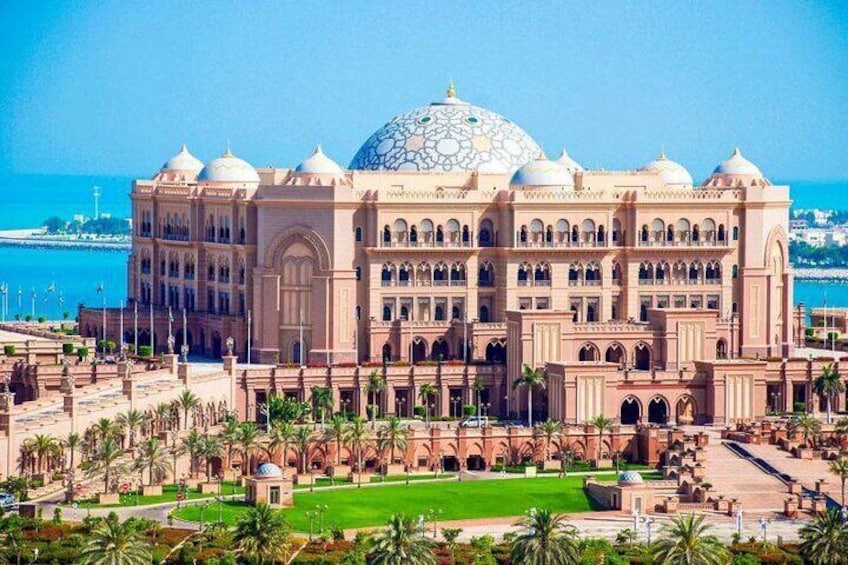 Emirates Palace: A luxurious Abu Dhabi hotel with golden domes, lush gardens, and a stunning seaside backdrop.