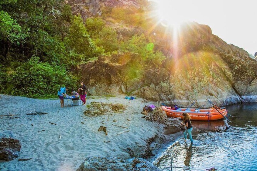 Group relaxing riverside as the sun fades over the Rogue River canyon