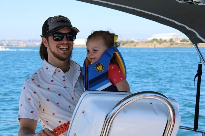 Dad and daughter laughing and taking a spin on the sailing charter