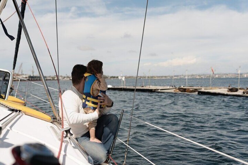 Family out sailing, visiting the san diego seals. Dad and daughter go out to the front to see the seals closer