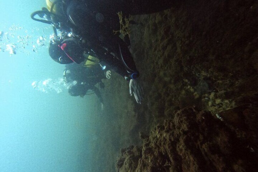 Divers warming their hands at the small hot water geyser at Secca delle Fumosa