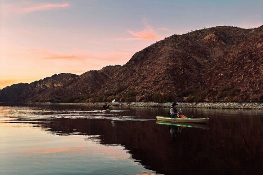 Kayakers catch a glimpse of whispy pink waves as the sun sets.