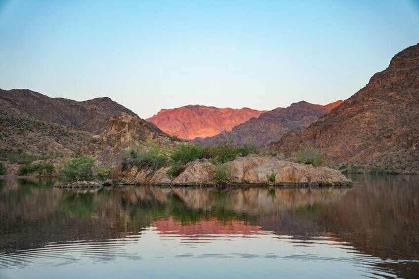 The sun casts shadows on the mountains as it begins to set.