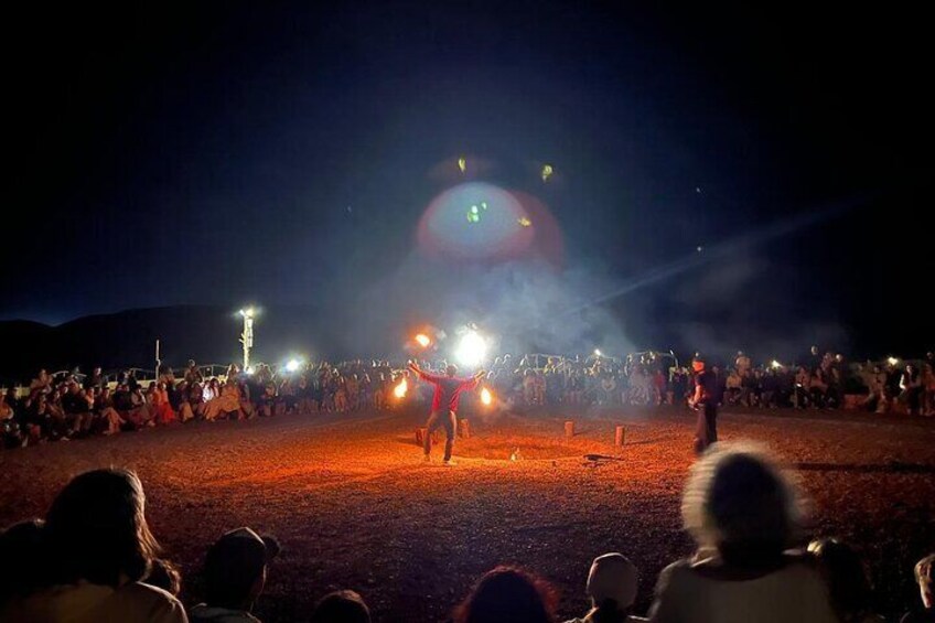 Immerse yourself in the enchanting atmosphere of the Agafay Desert with a captivating fire show surrounded by an excited audience under the night sky. The glowing flames, combined with the breathtakin