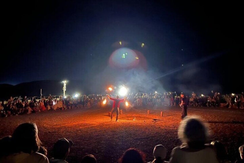 Immerse yourself in the enchanting atmosphere of the Agafay Desert with a captivating fire show surrounded by an excited audience under the night sky. The glowing flames, combined with the breathtakin