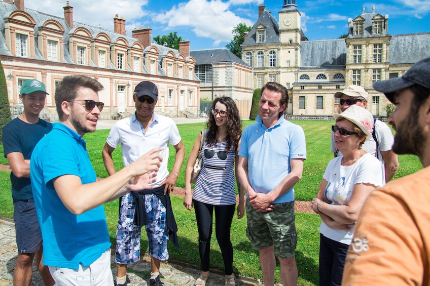 Tour guide speaks to group outside Fontainebleau 